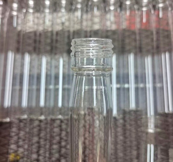 Backlit glass bottle from a Tianke production batch, with finished bottles behind